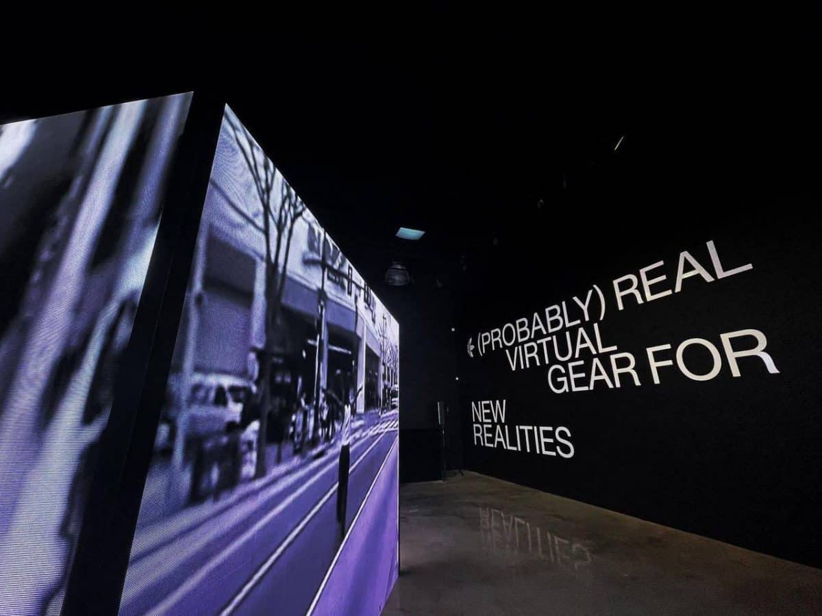 A black room with a lighted cube showing a video for Adidas.