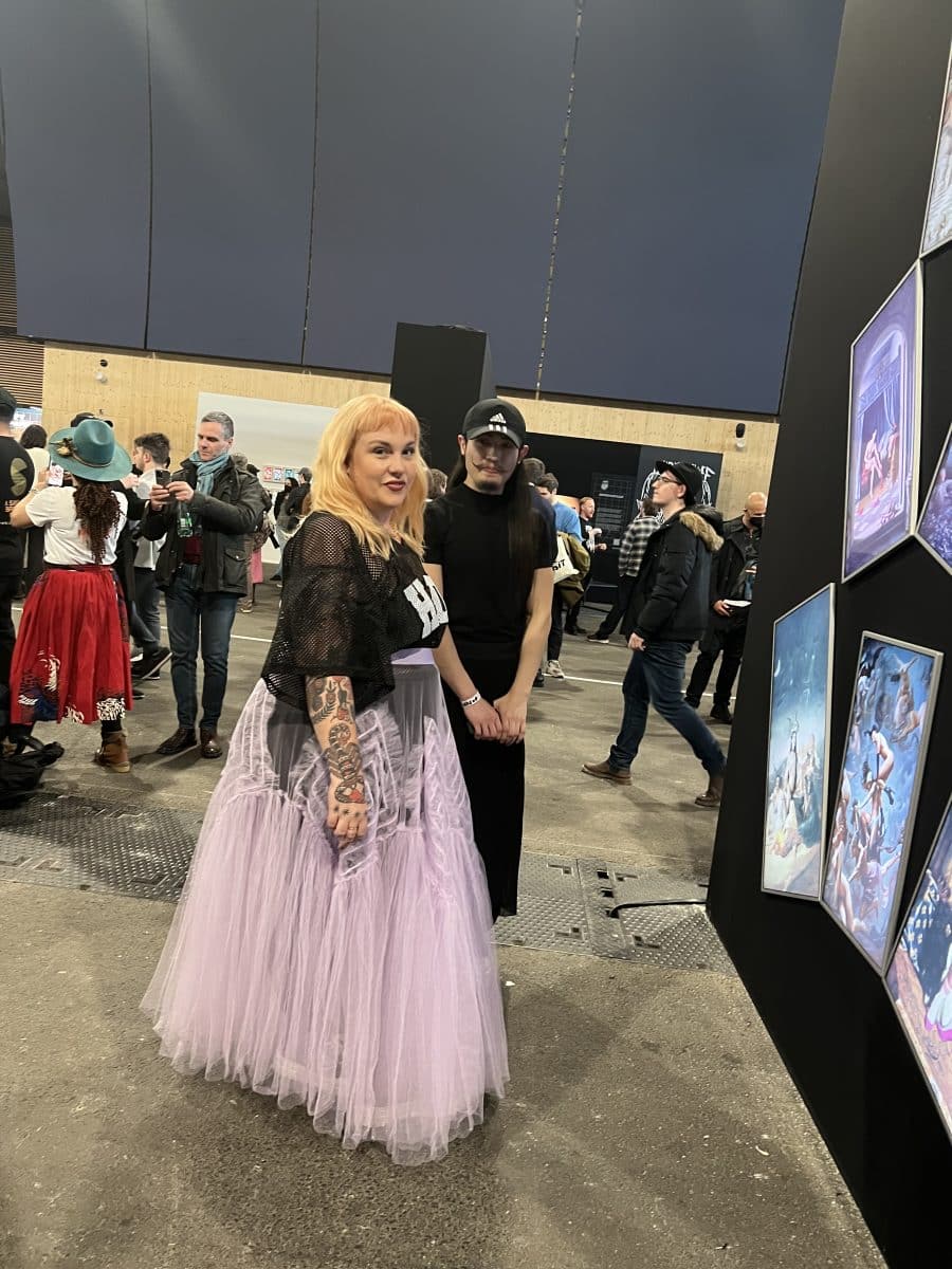 Two people Betty, CEO of Deadfellaz (In black top and long pin skirt), and the artist YuYu (dressed in all black) looking at an art installation