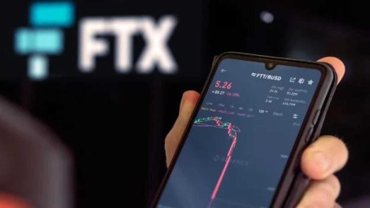 picture of a person holding up a phone that shows the crypto stock of FTX ($FTX) crashing to zero